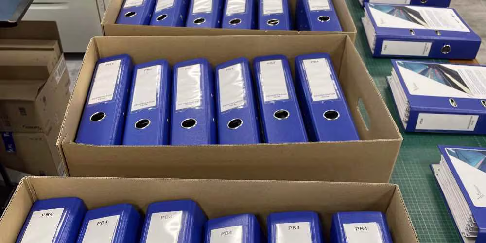 Dokumentacja powykonawcza w segregatorach gotowa do przekazania – niebieskie segregatory w pudłach